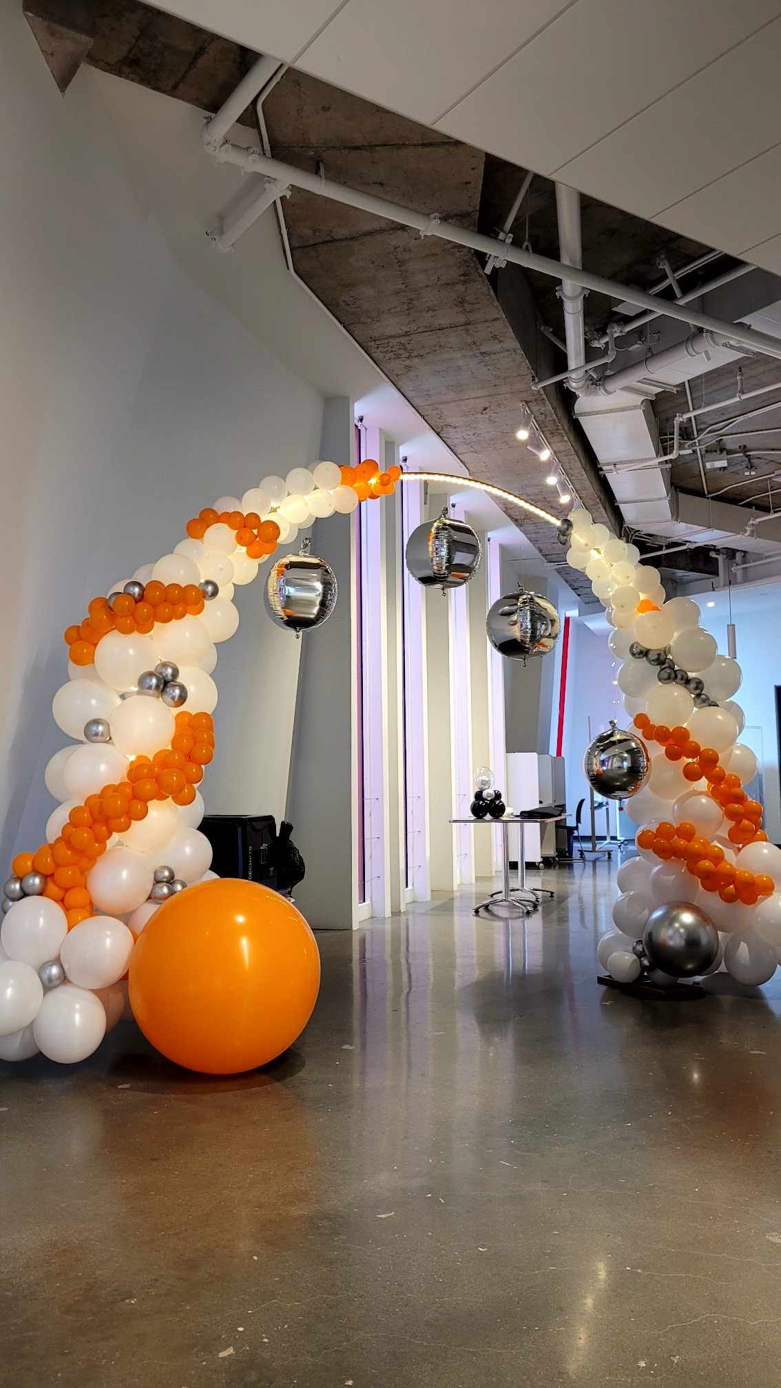 Arche de ballons orange et blancs montée par Nacréa pour un trentième anniversaire dans un sous-sol aménagé à Laval