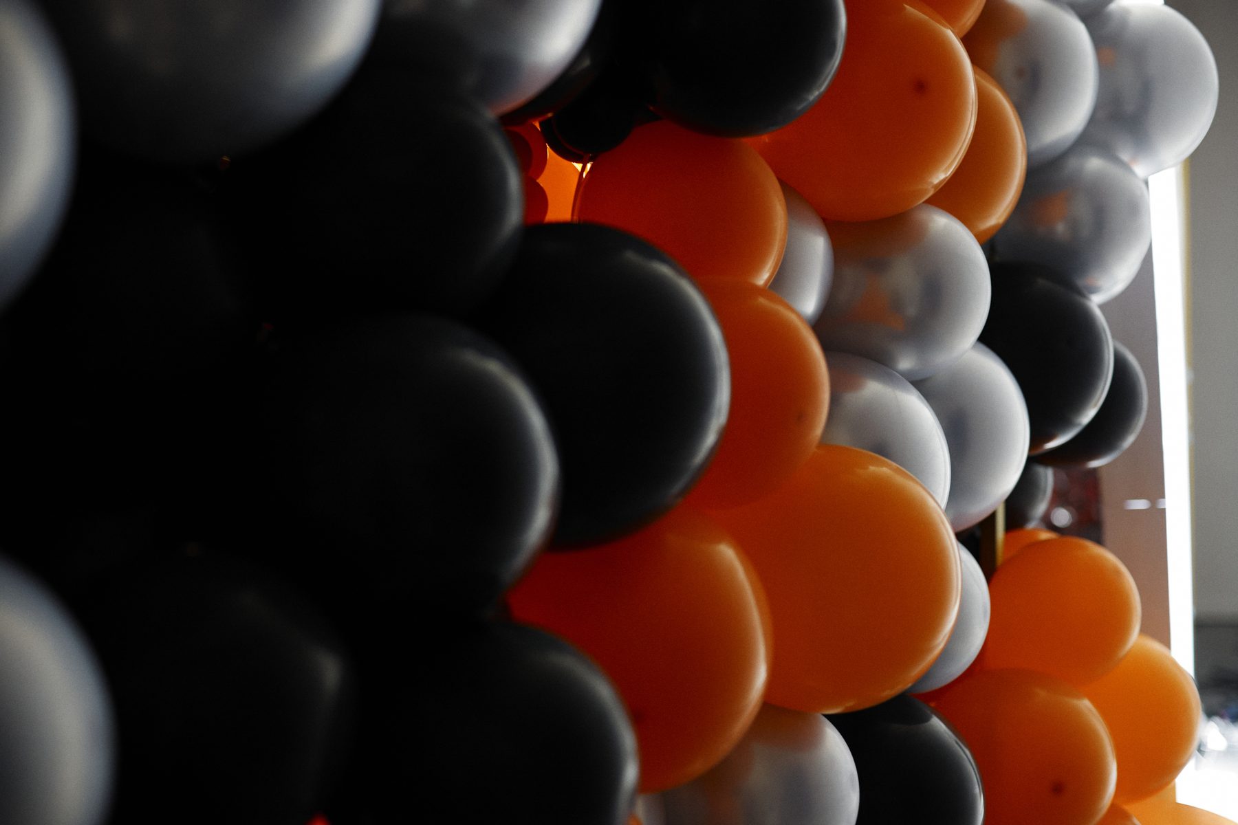 Mur de ballons noir, orange et argent monté par Nacréa à l'entrée du campus montréalais de l'École NAD, logo de l'école rétroéclairé au centre