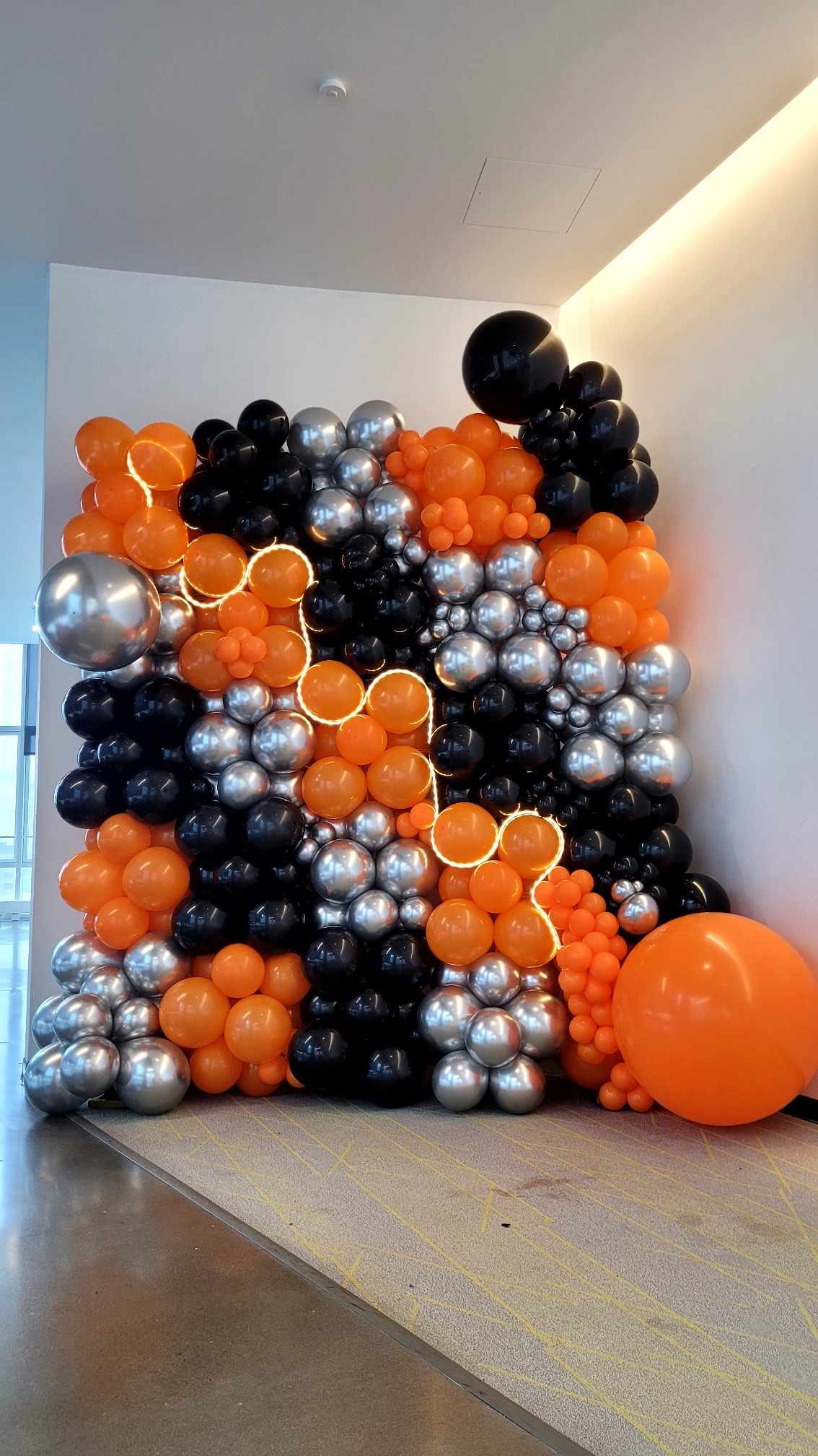 Arche de ballons orange, blancs et argent installée par Nacréa dans le hall du campus de l'École NAD à Montréal