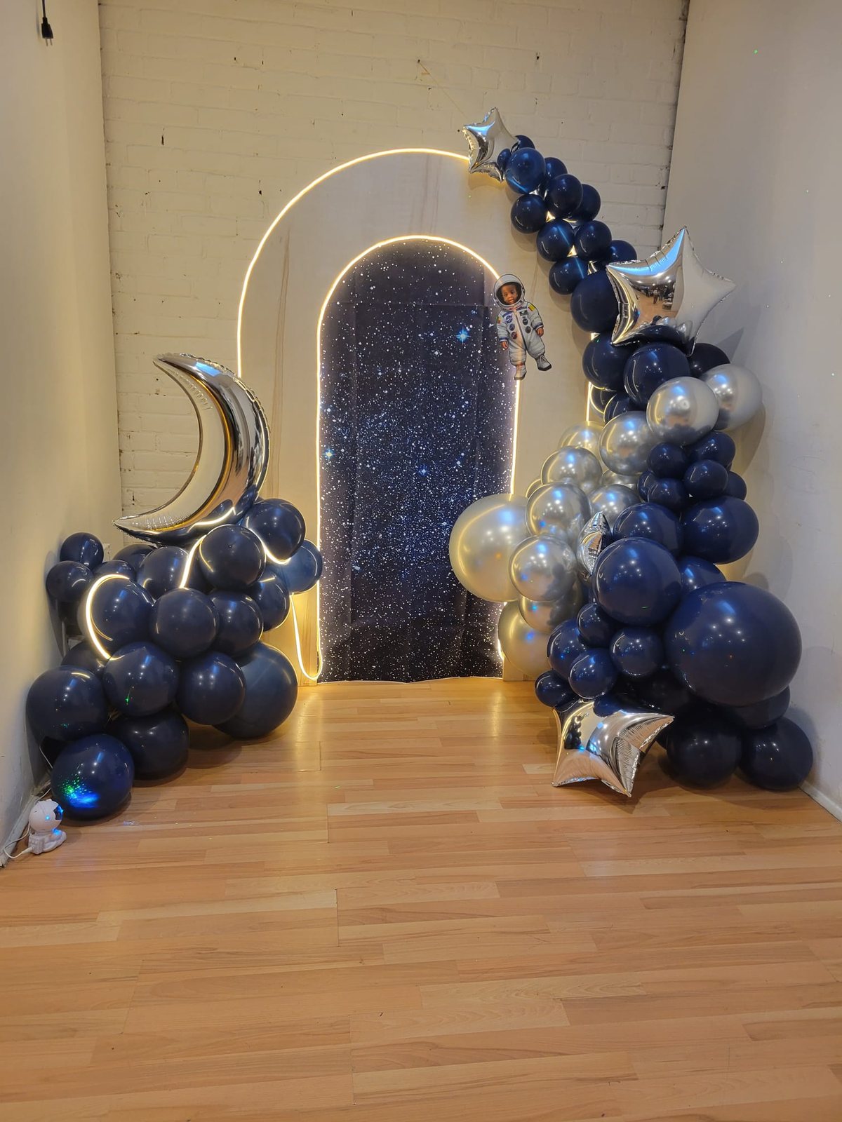 Toile de fond étoilée, arche lumineuse et guirlande de ballons bleu nuit et argent montées par Nacréa pour une fête prénatale sur la Rive-Sud